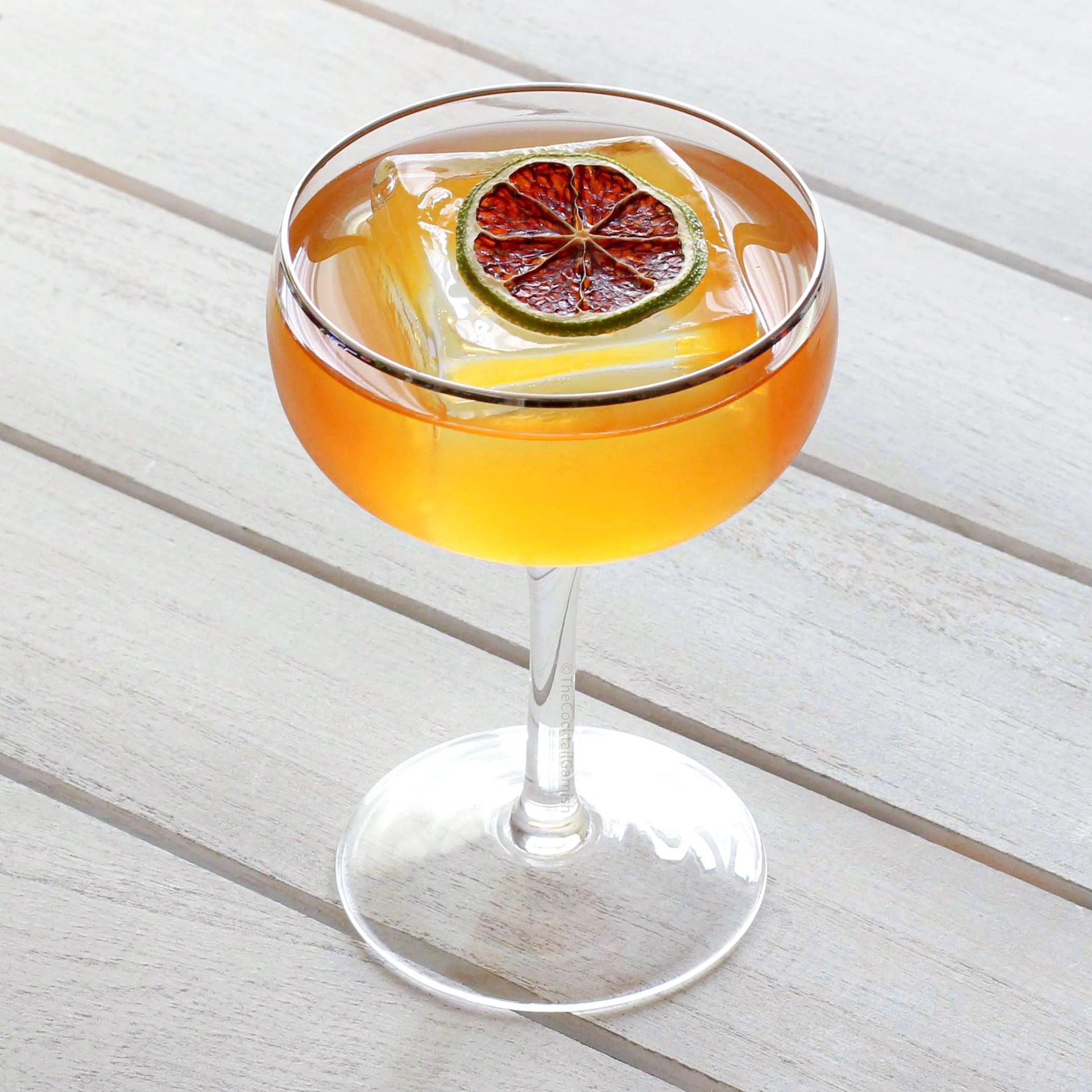 Load image into Gallery viewer, Cocktail in a glass with a lime wheel on a white wooden surface