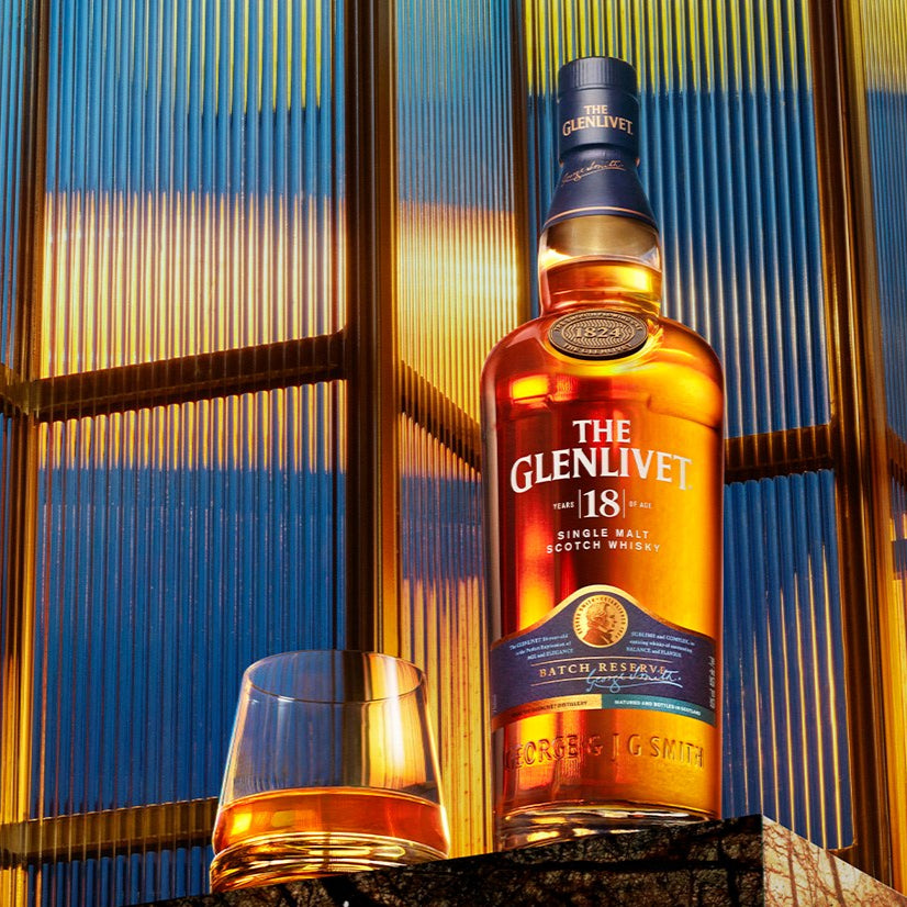 Load image into Gallery viewer, Glenlivet whisky bottle with a glass on a textured surface with abstract background