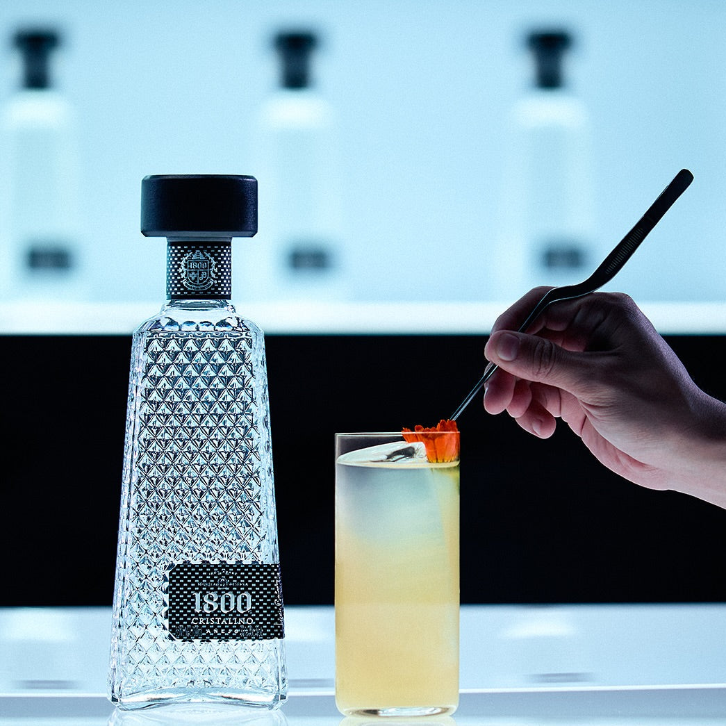 Load image into Gallery viewer, Bottle of 1800 Cristalino Añejo Jose Cuervo Tequila with a cocktail being stirred