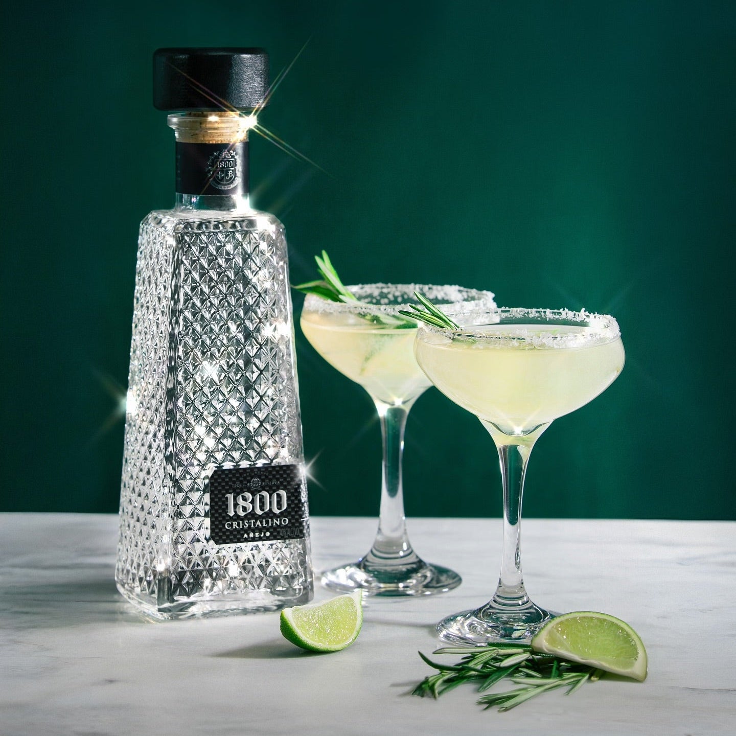 Load image into Gallery viewer, 1800 Cristalino Jose Cuervo Tequila bottle with two margaritas and lime wedges on a marble surface.