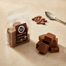 Load image into Gallery viewer, Chocolate fudge with a &#39;36bites&#39; label on a beige surface, surrounded by cocoa beans and a spoon.