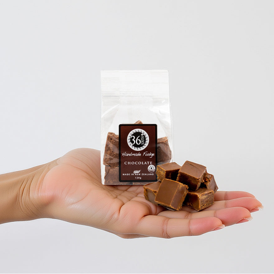 Load image into Gallery viewer, Woman hand holding pieces of 36 Degrees chocolate fudge with a 36 Degrees packet in the background