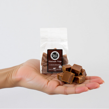 Load image into Gallery viewer, Woman hand holding pieces of 36 Degrees chocolate fudge with a 36 Degrees packet in the background