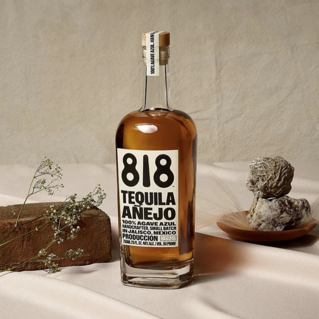 Bottle of 818 Tequila Añejo on a neutral background with decorative elements.