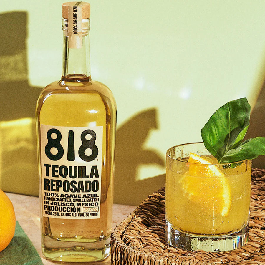 Load image into Gallery viewer, 818 Tequila Reposado bottle with a cocktail garnished with a lemon wedge on a woven tray.