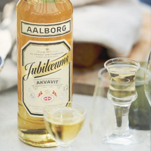 Load image into Gallery viewer, Aalborg Jubileums akvavit bottle with two shot glasses on a table.
