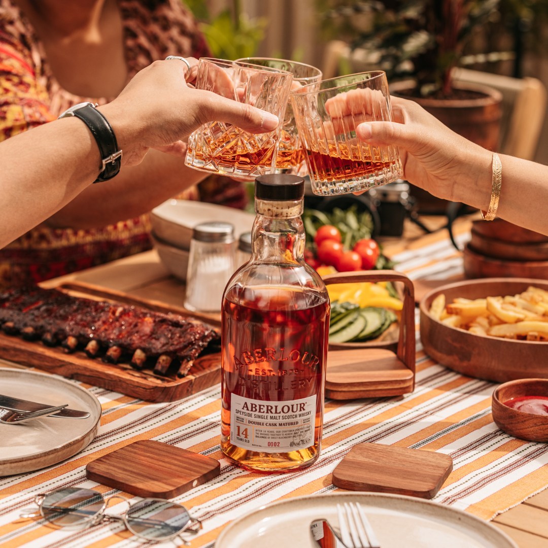 Load image into Gallery viewer, Two people toasting with Aberlour 14 year old whisky at a dining table with food and drinks.