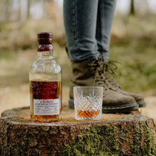 Load image into Gallery viewer, Bottle of Aberlour Abunadh whiskey and a glass on a tree stump in a forest setting