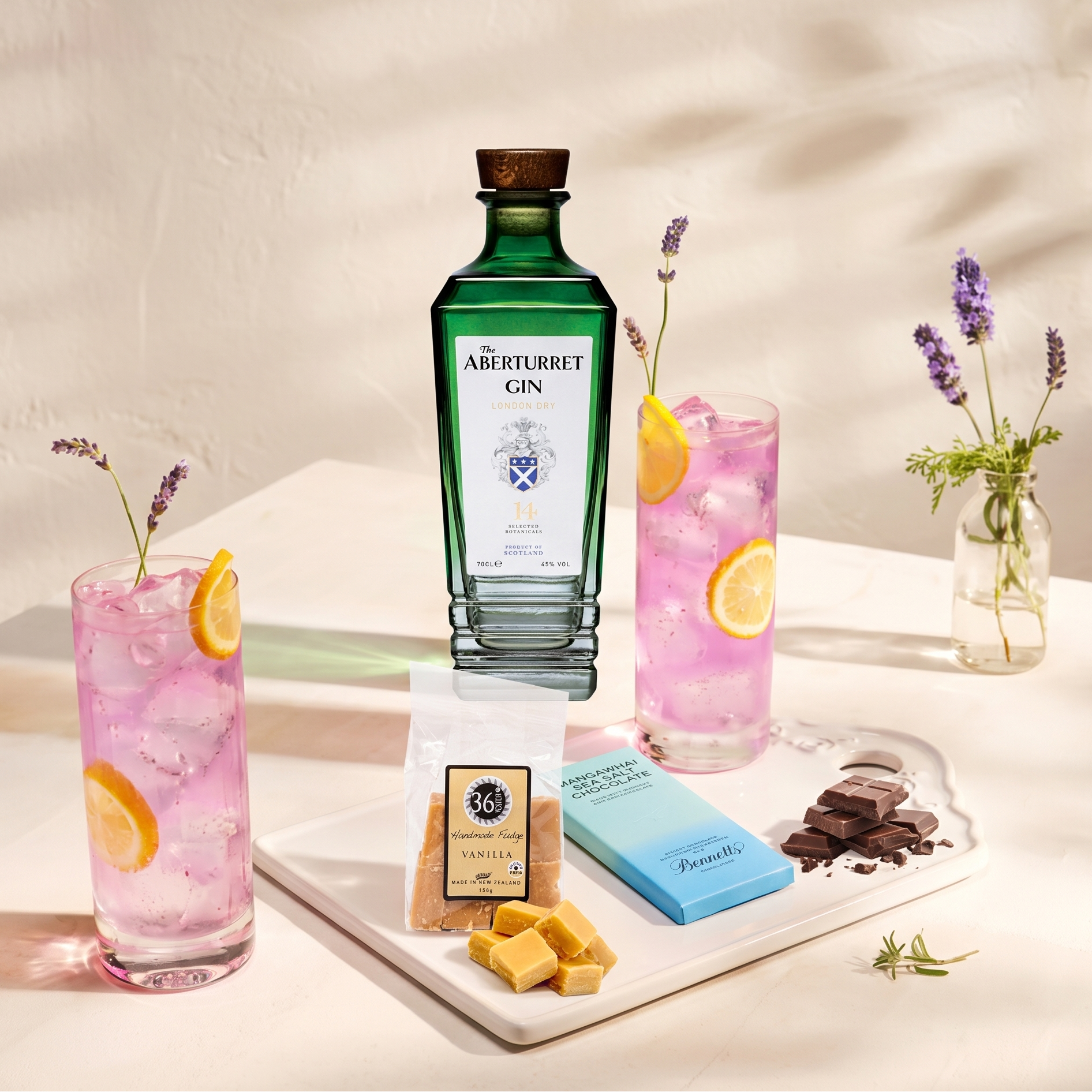 Load image into Gallery viewer, A bottle of Aberturret Gin stands on a white tray beside two pink gin cocktails with lemon slices, a bag of 36 Degrees vanilla fudge, a Bennett's Mangawhai Sea Salt chocolate bar, chocolate pieces, and small flower arrangements on a sunlit table.