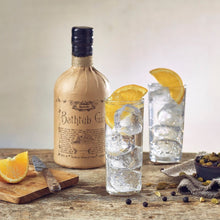Load image into Gallery viewer, Bottle of bathtub gin with two glasses of gin and tonic on a wooden table.