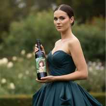 Load image into Gallery viewer, Woman in a teal dress holding a Adelina Wines Grenache wine bottle with a garden background