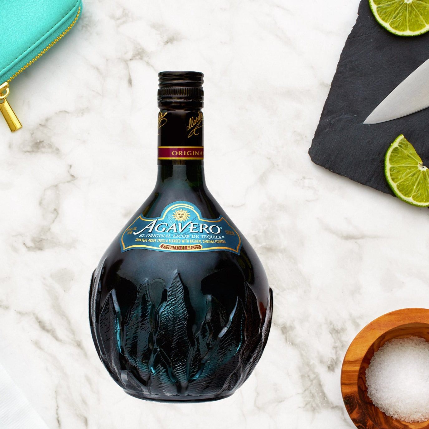 Load image into Gallery viewer, Agavero Tequila Liqueur bottle with limes and a knife on a marble surface