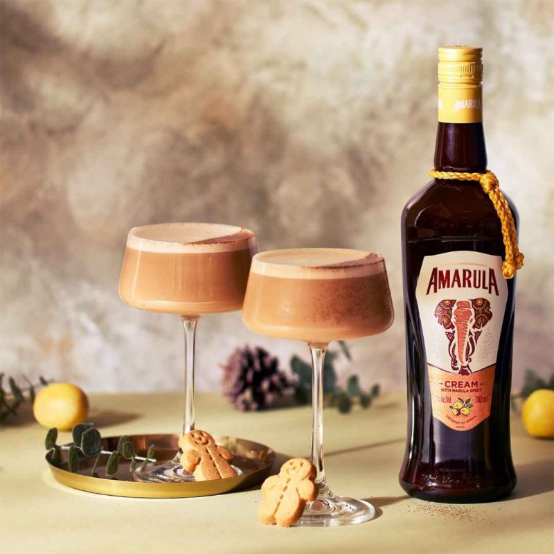 Load image into Gallery viewer, A bottle of Amarula Cream Liqueur and two cocktail glasses with Amarula in them with a Christmas setting on the table