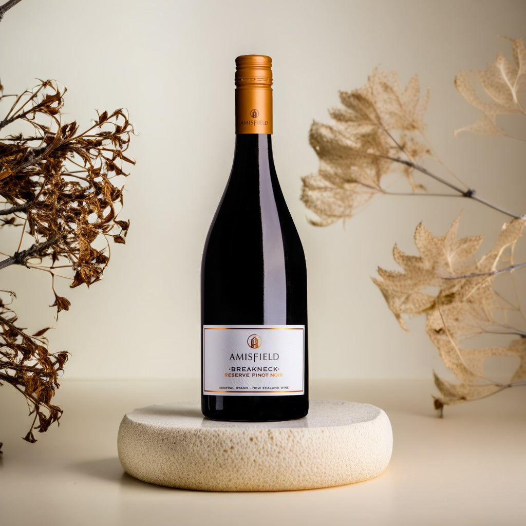 Amisfield-Pinot-Noir-breakneck wine bottle on a stone coaster with decorative elements in the background
