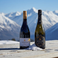 Load image into Gallery viewer, Two bottles of Amisfield wine on a wooden surface with snow-capped mountains in the background.