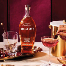 Load image into Gallery viewer, Bottle of Angels Envy bourbon with a cocktail glass and cherry on a table.