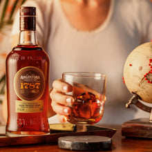 Load image into Gallery viewer, Bottle of Angostura 1787 rum with a glass of rum on a table.