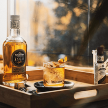 Load image into Gallery viewer, Angostura 1919 rum bottle with a cocktail on a wooden tray by a window.