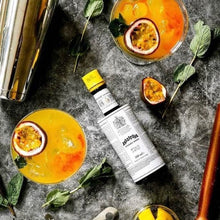 Load image into Gallery viewer, Cocktails with passion fruit, a bottle of Angostura Aromatic Bitters, and bar tools on a dark surface.