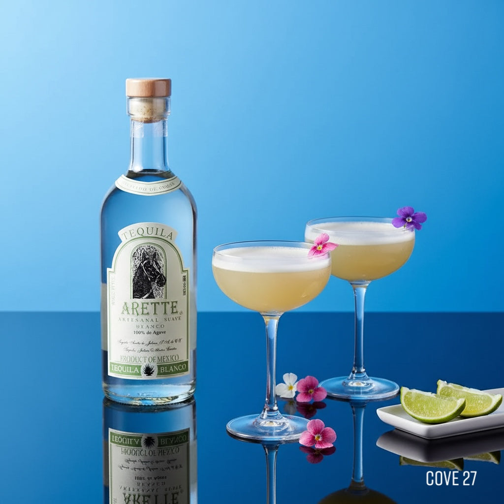 Load image into Gallery viewer, Bottle of Arette Artesanal Suave Blanco tequila with two cocktails and lime wedges on a blue background