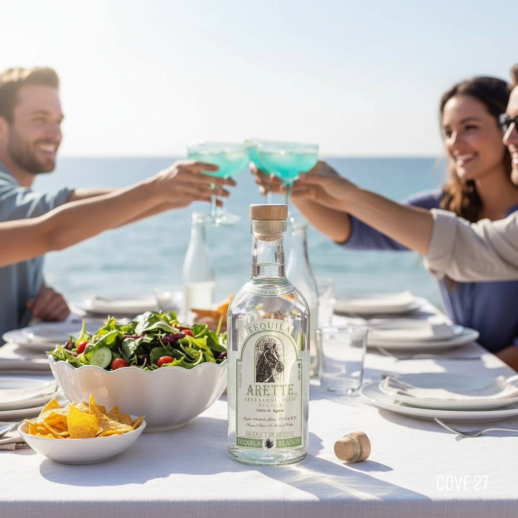 Load image into Gallery viewer, People toasting with drinks at a table by the ocean, with a bottle of Arette Artesanal Suave Blanco tequila in the foreground.