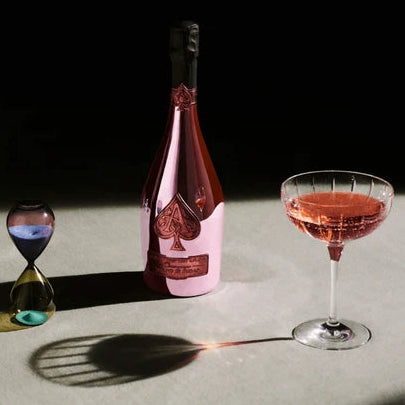 Load image into Gallery viewer, Bottle of Armand De Brignac Brut Rose champagne and glass of rosé champagne with a black background