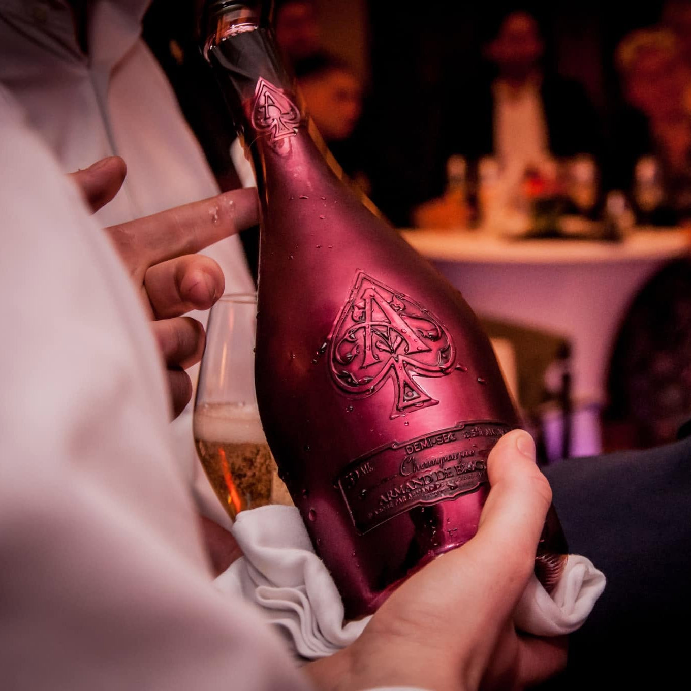 Load image into Gallery viewer, A waiter holding a pink bottle of Armand de Brignac Ace of Spades Rosé Champagne in an exclusive bar setting.