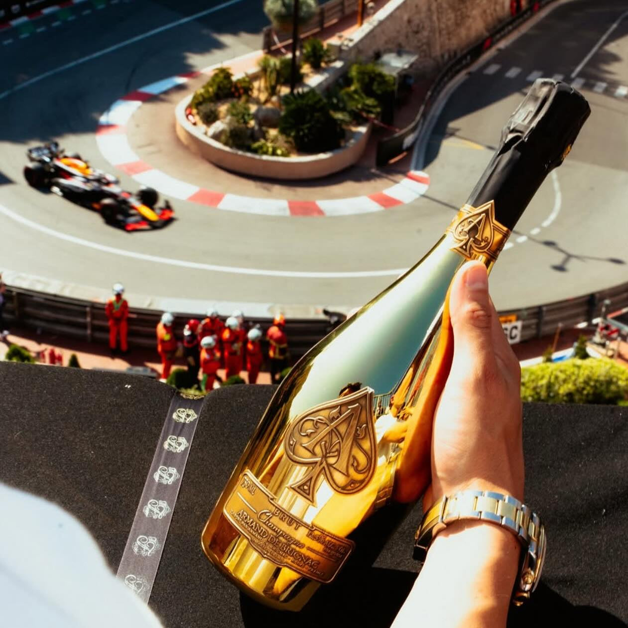 Load image into Gallery viewer, Hand holding a large champagne bottle with a race track in the background