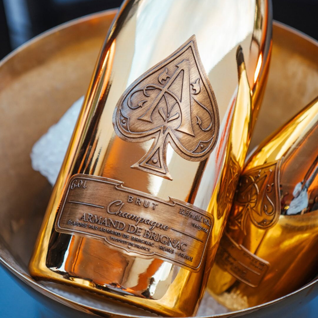 Load image into Gallery viewer, Two gold champagne bottles with a brand logo in an ice bucket.