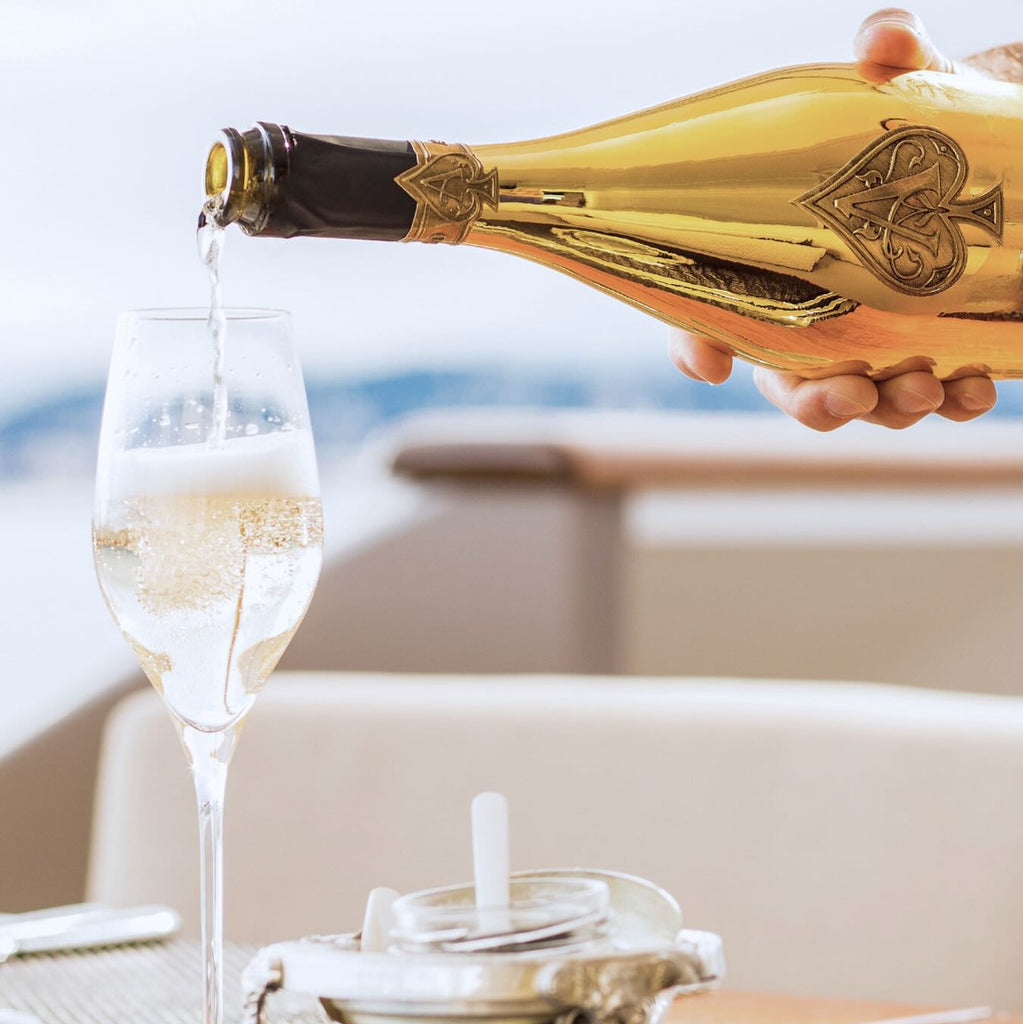 Bottle of champagne being poured into a glass on a table with a scenic background