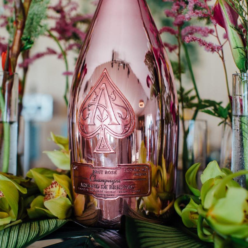 Rose gold bottle with brand logo surrounded by flowers