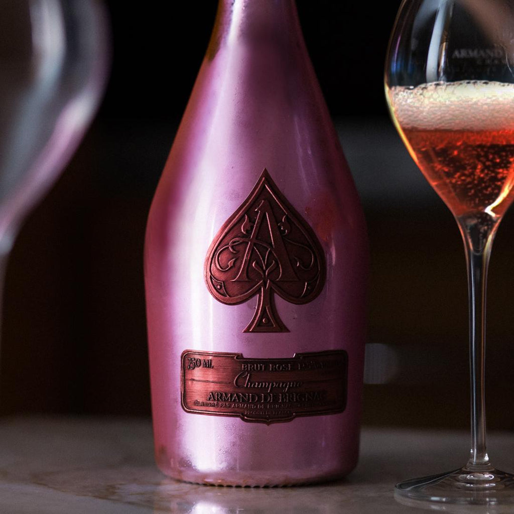 Pink champagne bottle with a spade symbol and a glass of champagne on a dark background