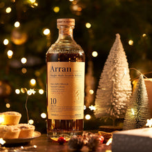 Load image into Gallery viewer, Arran 10 year old whisky bottle with Christmas decorations in the background