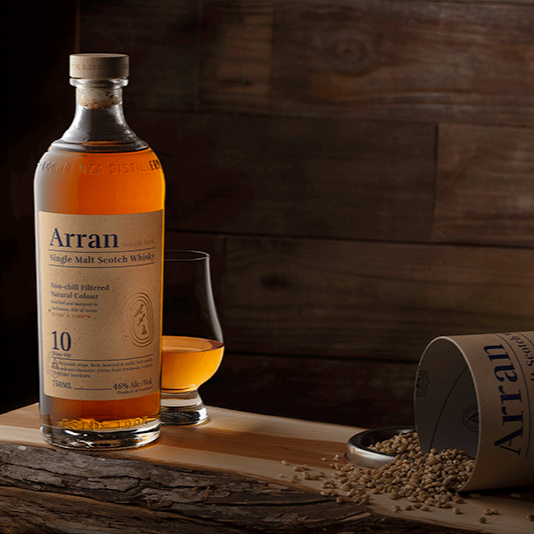 Arran whisky bottle and glass on a wooden surface with a wooden background