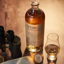 Load image into Gallery viewer, Arran 10 year old whisky bottle and glass on a wooden surface with binoculars and a map.