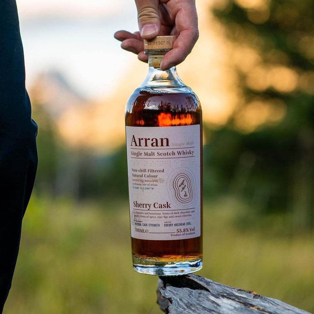 Bottle of Arran Sherry Cask whisky held by a person outdoors.