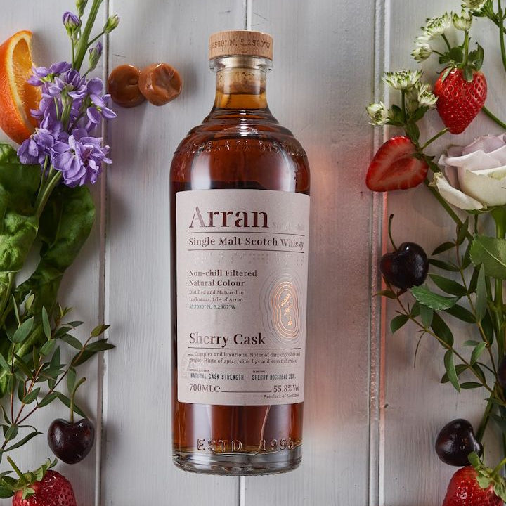 Arran Sherry Cask Scotch Whisky bottle with fruits and flowers on a light gray background