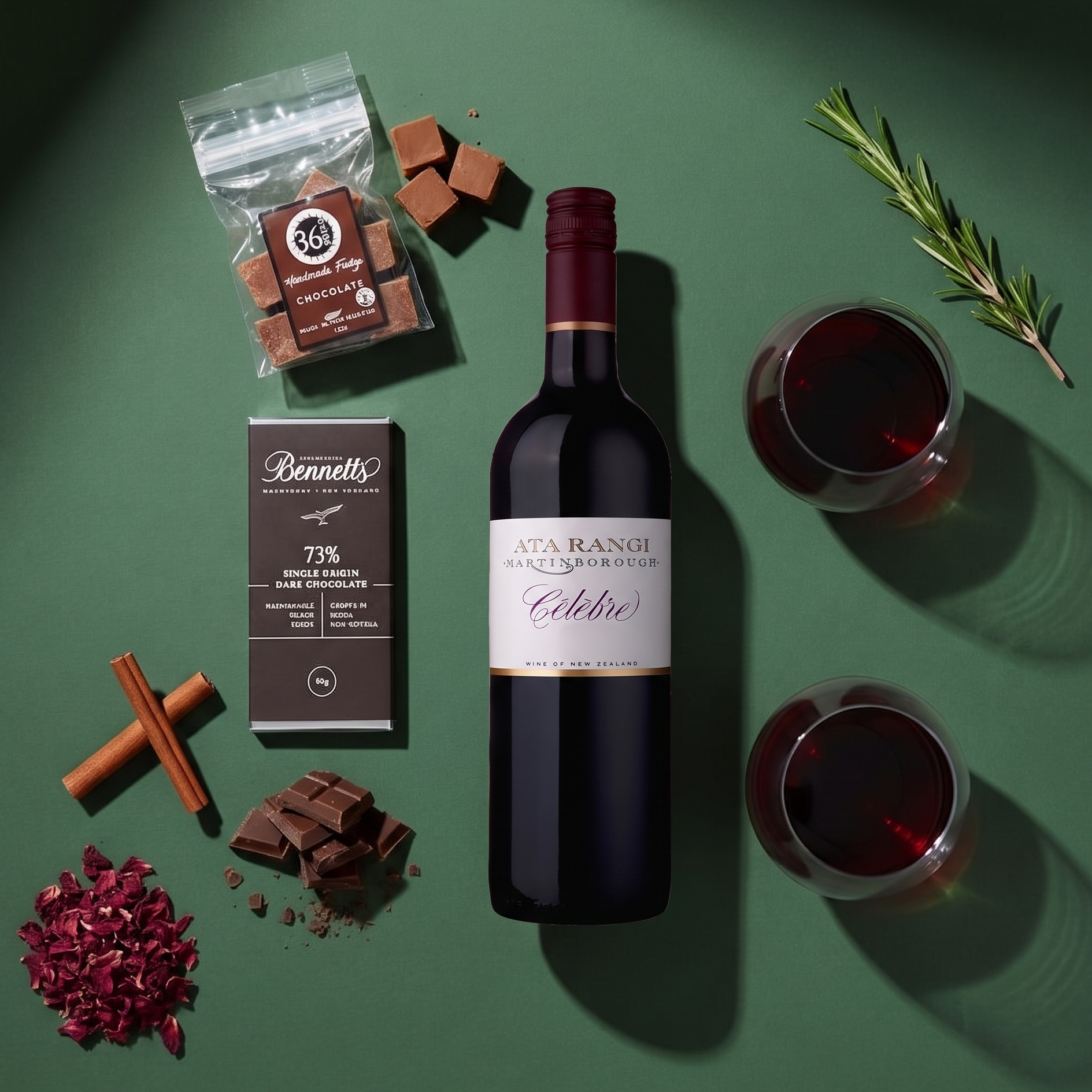 Load image into Gallery viewer, A styled flat-lay featuring a bottle of Ata Rangi Martinborough Célèbre red blend wine, a box of Bennett's 73% Dark Chocolate, and several chocolate pieces, a bag of 36 Degrees chocolate fudge, arranged on a dark green background with glasses of red wine, rosemary, cinnamon sticks, and dried rose petals.