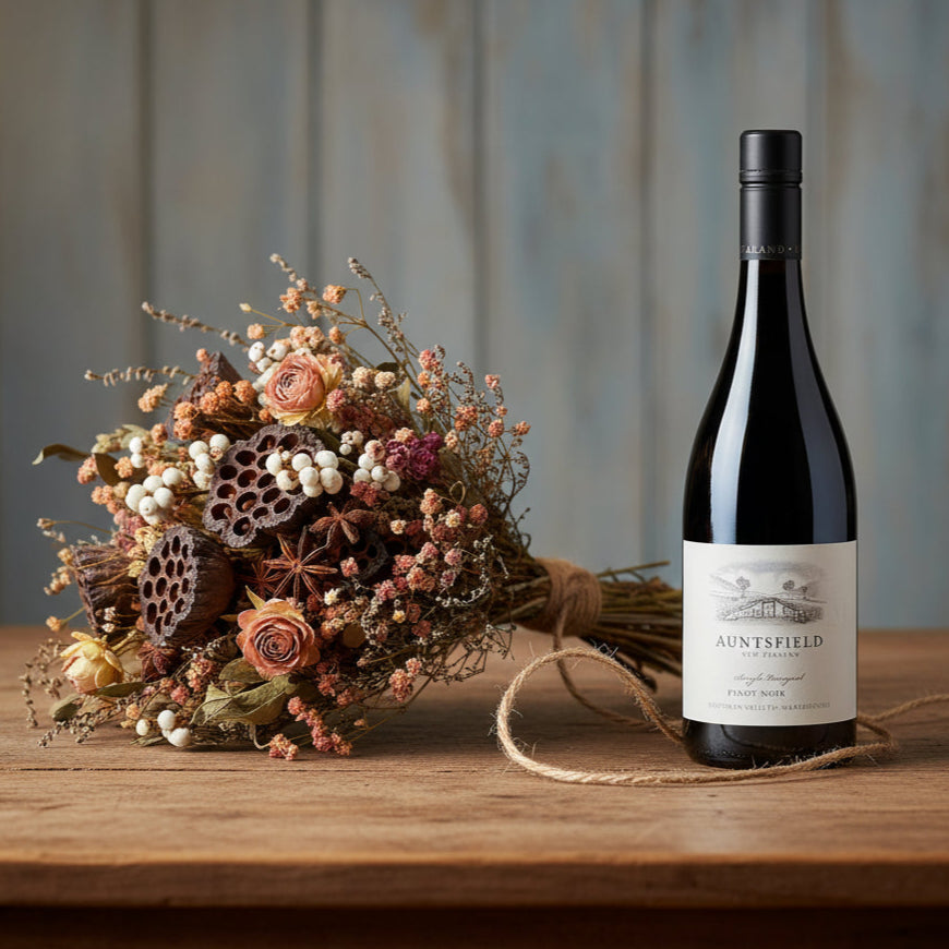 Load image into Gallery viewer, Bottle of Auntsfield-Single-Vineyard-Pinot-Noir wine with a bouquet of flowers on a wooden table