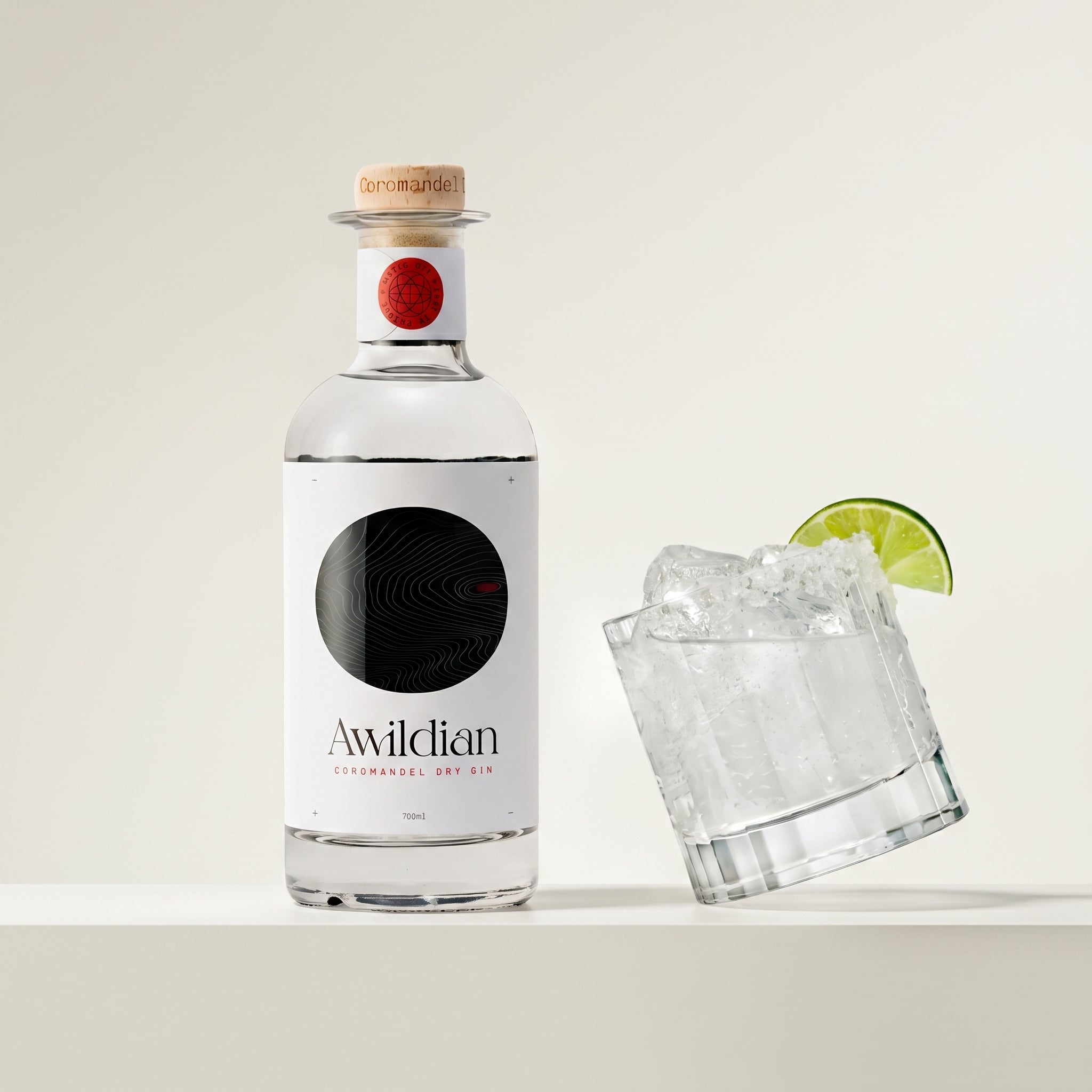 Load image into Gallery viewer, Bottle of Awildian dry gin with a glass of ice and lime wedge on a white background