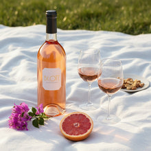 Load image into Gallery viewer, Bottle of BY.OTT Provence Rose Magnum wine with two glasses and a half-eaten grapefruit on a white blanket outdoors.