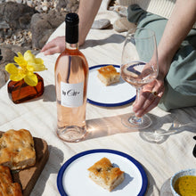 Load image into Gallery viewer, Person sitting on a blanket with a bottle of BY-OTT Provence Rose wine, glasses, and plates of food outdoors.