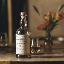 Load image into Gallery viewer, Balvenie 12 year old whiskey bottle on a wooden table with blurred background