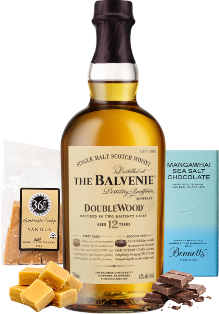 A bottle of The Balvenie DoubleWood 12yo single malt Scotch whisky is centred, flanked by a bag of 36 Degrees Handcrafted Vanilla fudge, a blue box of Bennetts Mangawhai Sea Salt Chocolate, and caramel and dark chocolate pieces on a white background.