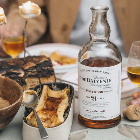 Balvenie 21 YEAR OLD whisky bottle on a dining table with food and glasses