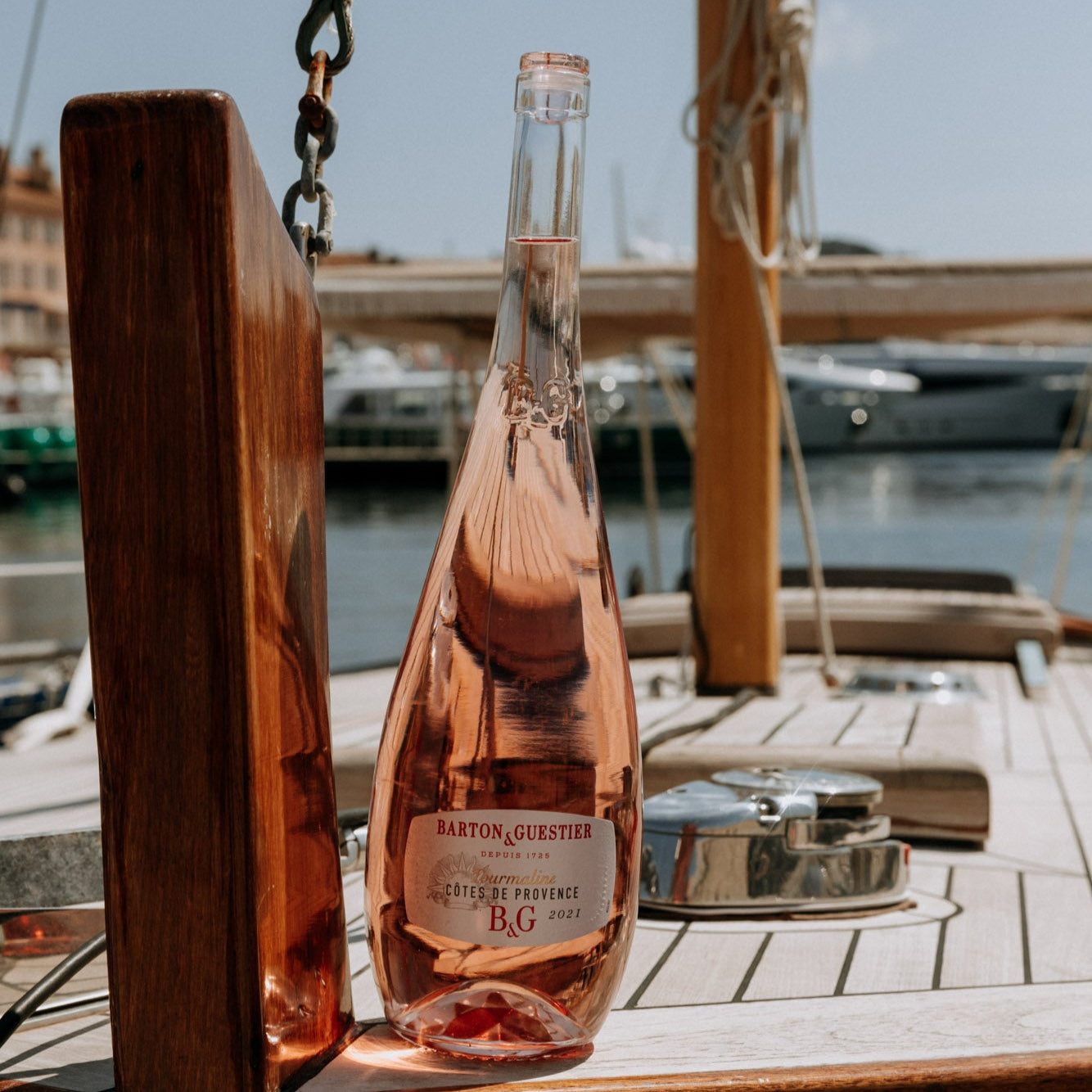 Load image into Gallery viewer, Bottle of rose wine on a wooden surface with a marina background