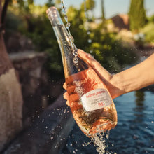 Load image into Gallery viewer, A woman holding a a bottle of rose wine and some water splashing around it.