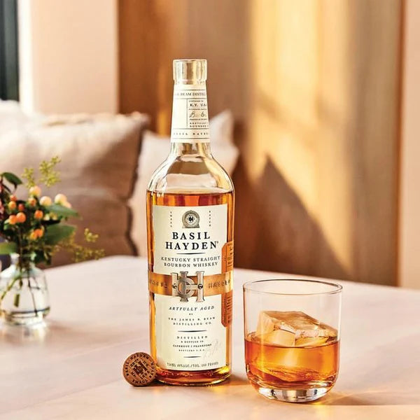 Load image into Gallery viewer, Bottle of Basil Hayden whiskey with a glass of whiskey on a table.