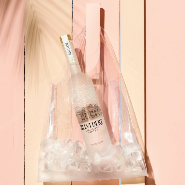Load image into Gallery viewer, Bottle of Belvedere Vodka on ice with a pink and yellow gradient background