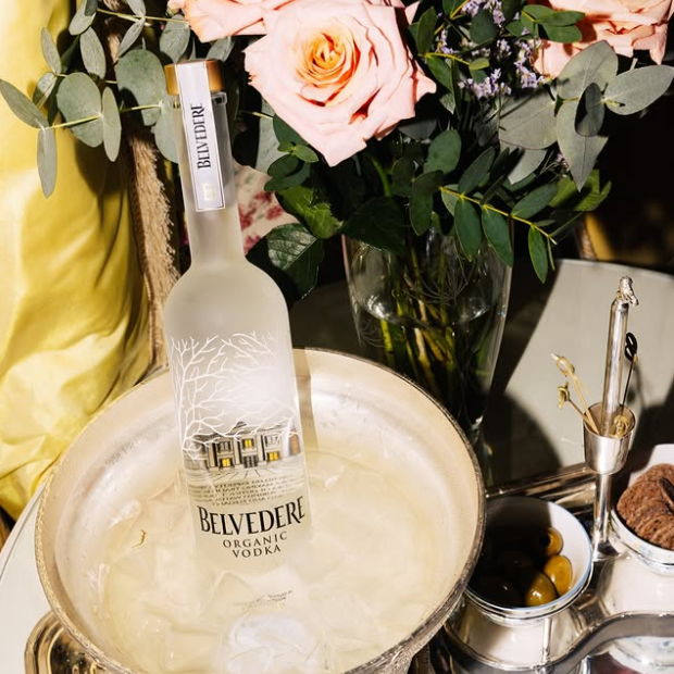 Load image into Gallery viewer, Belvedere vodka bottle in an ice bucket with flowers in the background